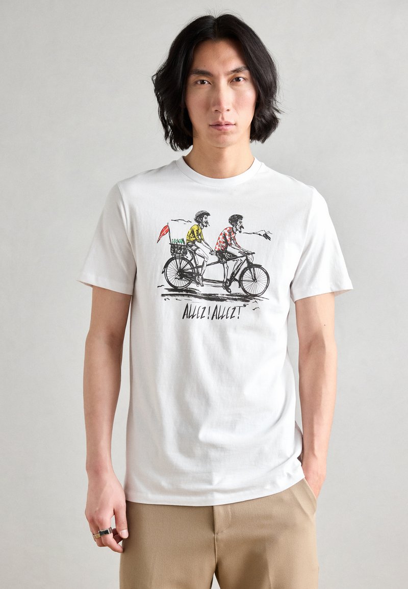 White cotton t-shirt featuring a printed illustration of two cyclists, with one in yellow and the other in red, and text "Allez! Allez!" below.