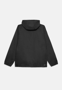 Veste légère noire avec capuche, poignets élastiques et ourlet droit. Fabriquée en matériau lisse et résistant à l'eau, sans motifs visibles.