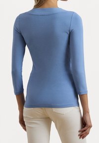 Blå långärmad topp med rund halsringning och slim fit, tillverkad av ett mjukt, stretchigt tyg, med subtila sömdetaljer och en ren fåll.