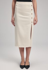 Falda midi color crema con una abertura lateral, detalle de botones y un dobladillo deshilachado. El material parece ligero y suave, realzando su forma estructurada.