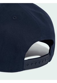 Casquette bleu marine en tissu texturé, avec un visière incurvée et une sangle en plastique réglable dotée de plusieurs trous pour un ajustement de la taille.