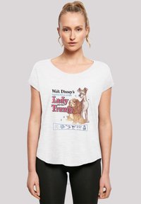 Hvit T-skjorte med korte ermer som har et fargerikt tegneserie-design av to hunder og teksten "Lady and the Tramp." Myk, avslappet passform.
