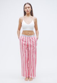 Ροζ και λευκό ριγέ παντελόνι με φαρδιά πόδια και ελαστική μέση με το λογότυπο "Juicy Couture". Συνδυάζεται με απλό λευκό crop top.