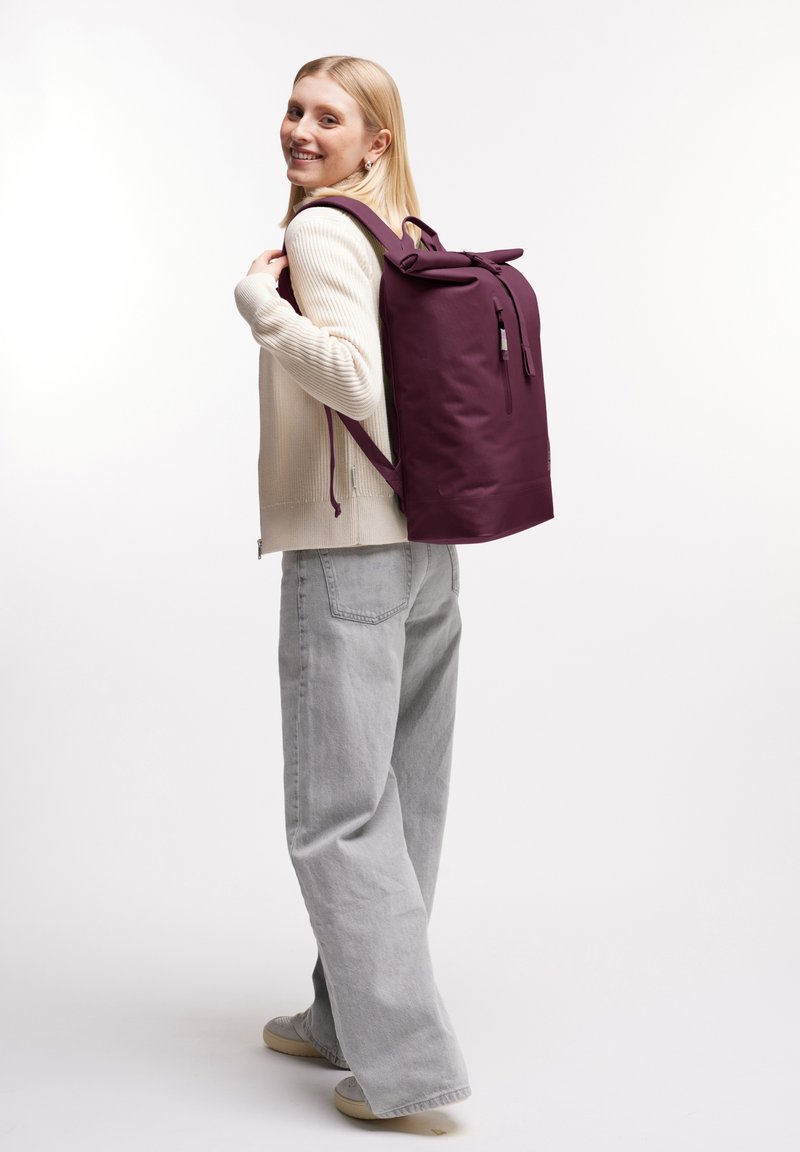 Zaino bordeaux realizzato in materiale durevole, con un design semplice, chiusura a cordoncino e tasca frontale con zip. Spallacci regolabili.