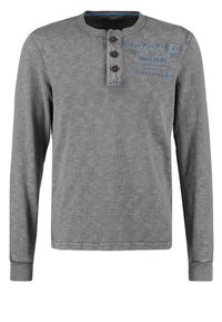 Graues Langarm-Henley-Shirt mit drei Knöpfen und einem blauen Textlogo auf der linken Brust, das "Napapijri Sales Co Inc 1967" liest.