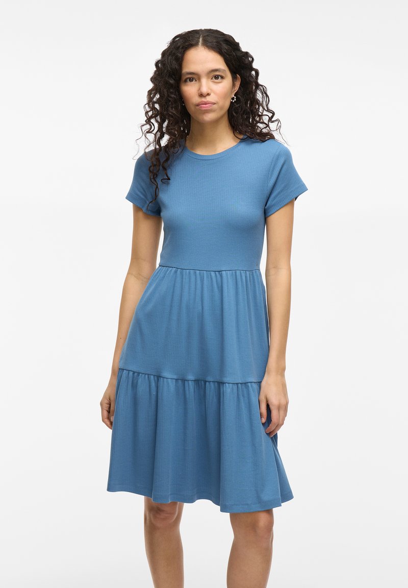 Robe bleu à manches courtes avec un haut ajusté et une jupe évasée à plusieurs niveaux. Fabriquée en tissu côtelé, elle dispose d'un col rond et d'une texture douce.