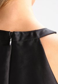 Czarna sukienka bez rękawów z okrągłym dekoltem. Posiada zamek błyskawiczny ukryty z tyłu oraz gładki, teksturowany materiał.