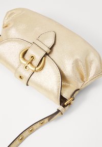 Goldfarbene metallische Clutch-Tasche mit einer strukturierten Oberfläche, die über einen Schnallenverschluss und einen abnehmbaren Tragegurt verfügt, betont durch goldene Beschläge.