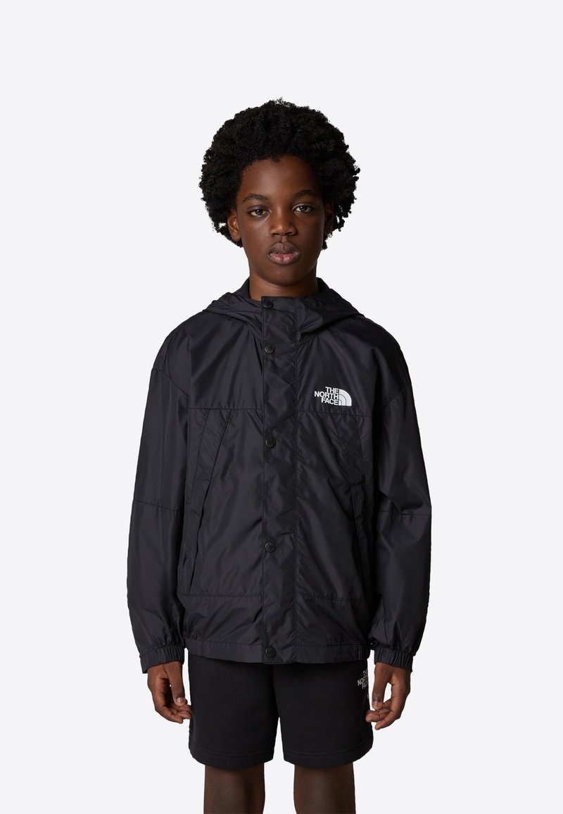 Svart vattentät jacka med huva, framknapning och elastiska ärmmuddar. Har en vit logga på bröstet. Slätt, lätt tyg.