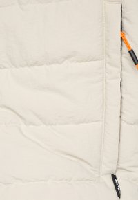 Wit gewatteerde jas met een gladde textuur, voorzien van oranje koordhardware en zwarte ritsaccenten. Compact ontwerp met gestikte panelen.