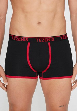 Czarne bokserki męskie z czerwonym wykończeniem i nadrukiem "TEZENIS" na czerwono na gumce, noszone przez stojącą osobę od talii do górnej części ud.