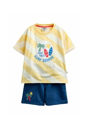 Gul og hvid stribet t-shirt med "Surf Seeker" og grafik af surfboard, palme og sol, kombineret med blå shorts med palme og surfboard patch.