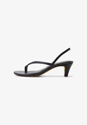 Sandalia slingback de cuero negro con tacón bajo tipo kitten y tira en forma de T en el dedo, diseño minimalista sobre fondo blanco.