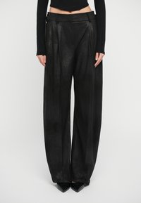 Black wide-leg trousers made from a textured material, featuring pleats, a high waist, and a decorative belt with hardware accents.