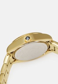 Orologio in acciaio inox dorato con cassa e bracciale lisci. Presenta una corona prominente e un fondello argentato texturizzato, contrassegnato "RESISTENTE ALL'ACQUA".