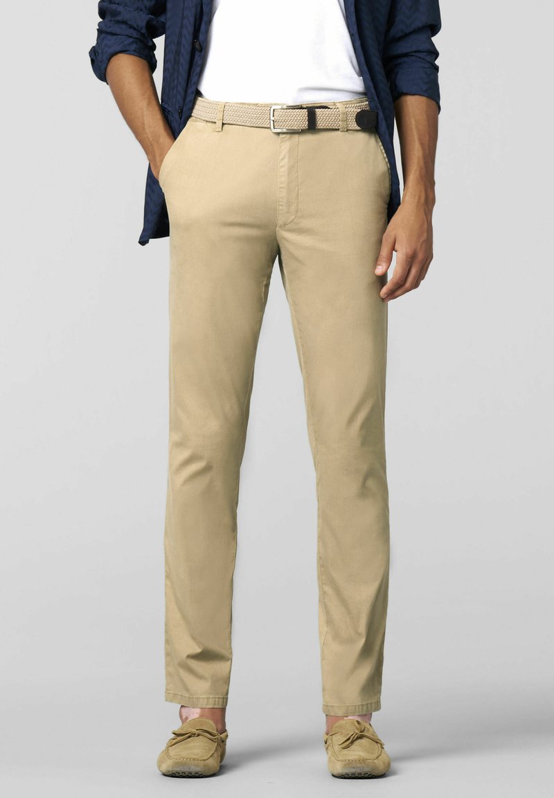 Beige chinos with a straight fit, featuring belt loops and a woven belt. Paired with casual slip-on shoes and a blue shirt.