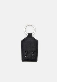 Schwarzer Leder-Schlüsselanhänger mit strukturierten Oberflächen, der eine kantige Form hat und mit geprägtem "AIX"-Schriftzug versehen ist. Silberner Metallring zur Befestigung.