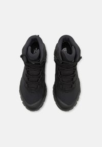 Black hiking shoes featuring a textured upper, reinforced toe, flexible laces, padded collar, and a rugged sole for traction.