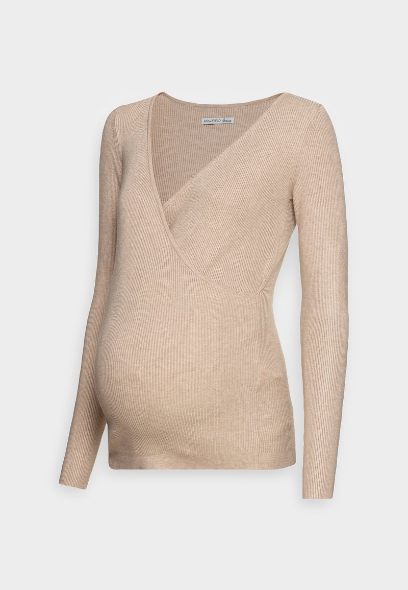 Pull de maternité beige côtelé à manches longues avec col en V et design cache-cœur sur un fond clair uni.