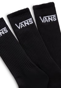 Calzini neri a costine con il logo bianco "VANS" sul bordo superiore. Tessuto morbido, lunghezza alla caviglia, progettati per comfort e durabilità.