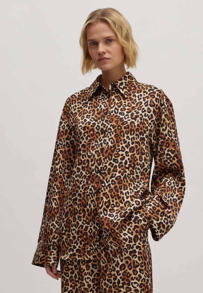 Leopardprint shirt in een glanzende stof; heeft een puntige kraag, lange mouwen en een relaxte pasvorm met variaties van bruin, zwart en crème.