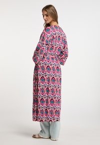 Dolga, ohlapna kimono v roza barvi z večbarvnimi geometrijskimi vzorci. Ima pas z obrobo in široke rokave, izdelana iz lahkega materiala.