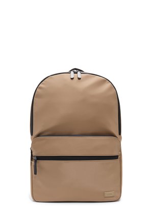 Mochila de nailon beige con forma redondeada, que cuenta con un bolsillo frontal con cremallera, acentos negro mate y herrajes plateados en las cremalleras dobles.