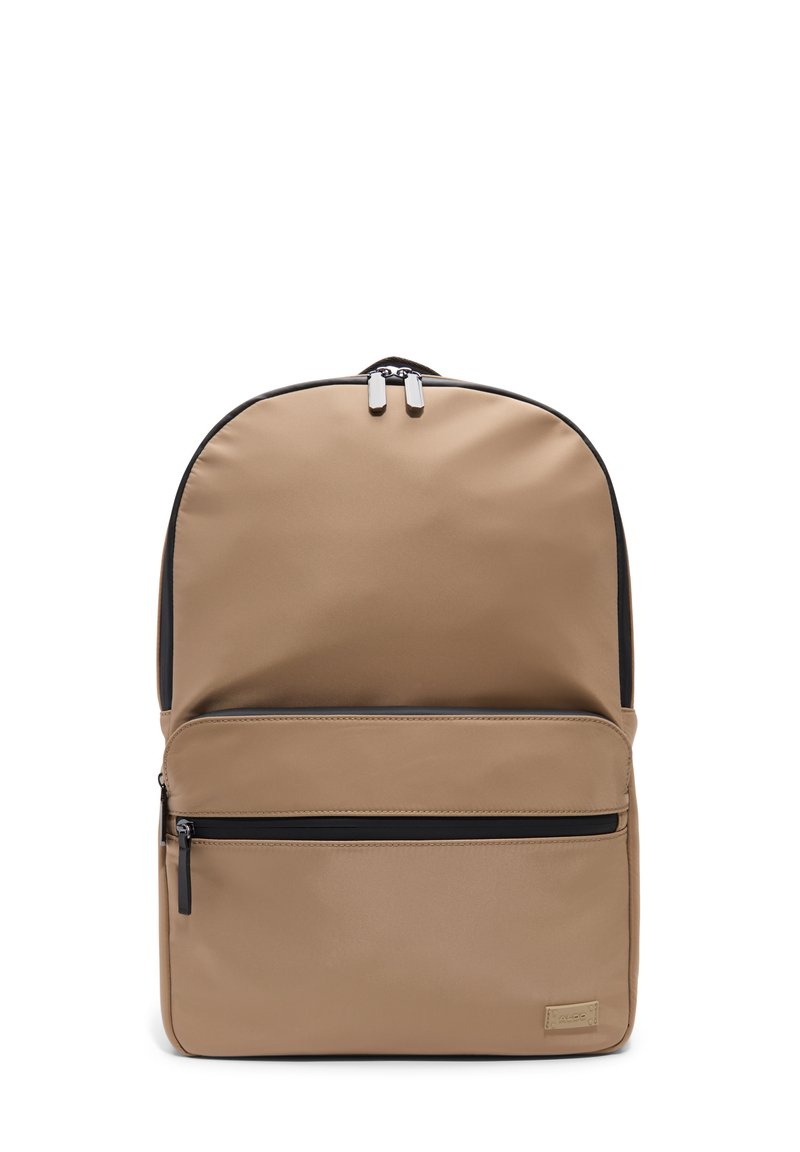 Sac à dos en nylon beige de forme arrondie, avec une poche zippée à l'avant, des accents noir mat et des accessoires en argent sur les double zips.