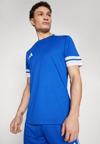 Blue athletic shirt with white stripes on sleeves, soft fabric, crew neckline, featuring three vertical stripes logo on the chest.