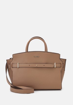 Jasnobrądziana torebka Calvin Klein z górnymi uchwytami, detalem przedniego paska i odpinanym paskiem na ramię, pokazana na jednolitym jasnym tle.