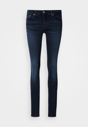 Tumši zili šauras džinsa bikses ar piecu kabatu dizainu, jostas cilpām un pogas aizdari. Gluda tekstūra ar smalku šuvumu.