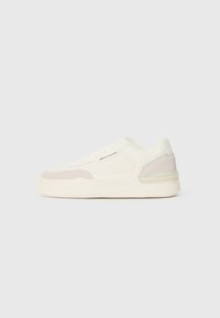 White leather sneakers with light grey suede accents, round toe, lace-up front, and a textured sole. Branding visible on the side.