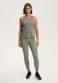 Olive green athletic tank top and leggings set, made from smooth, stretchy material, paired with black running shoes. Simple design, no patterns.