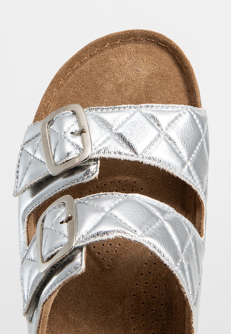 Silberne, gesteppte Sandalen mit zwei verstellbaren Riemen, ausgestattet mit rechteckigen Metall-Schnallen und einer weichen, braunen Wildleder-Fußbett.