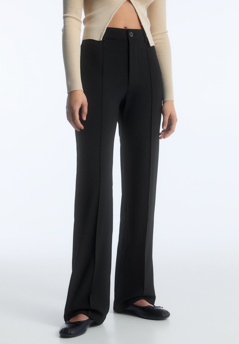 Schwarze, taillierte Hose mit hoher Taille und weit ausgestellten Beinen, ausgestattet mit einem vorderen Knopfverschluss und seitlichen Nähten für einen klaren, strukturierten Look.