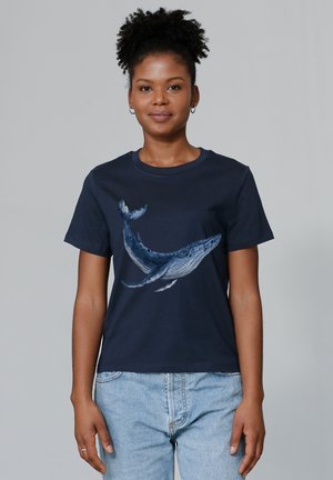 T-shirt en coton bleu marine avec un graphisme de baleine dans des nuances de bleu. Manches courtes, col rond et coupe décontractée.