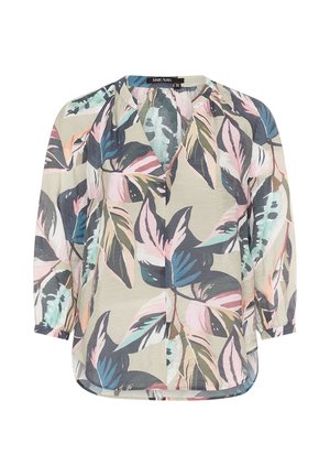 Women’s loose blouse with long sleeves and pastel multicolor large tropical leaf print on beige background.