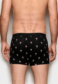 Sorte bokser-shorts med et gentaget mønster af kranier og julestråhat. Lavet af strækbart stof med et tætsiddende talje.