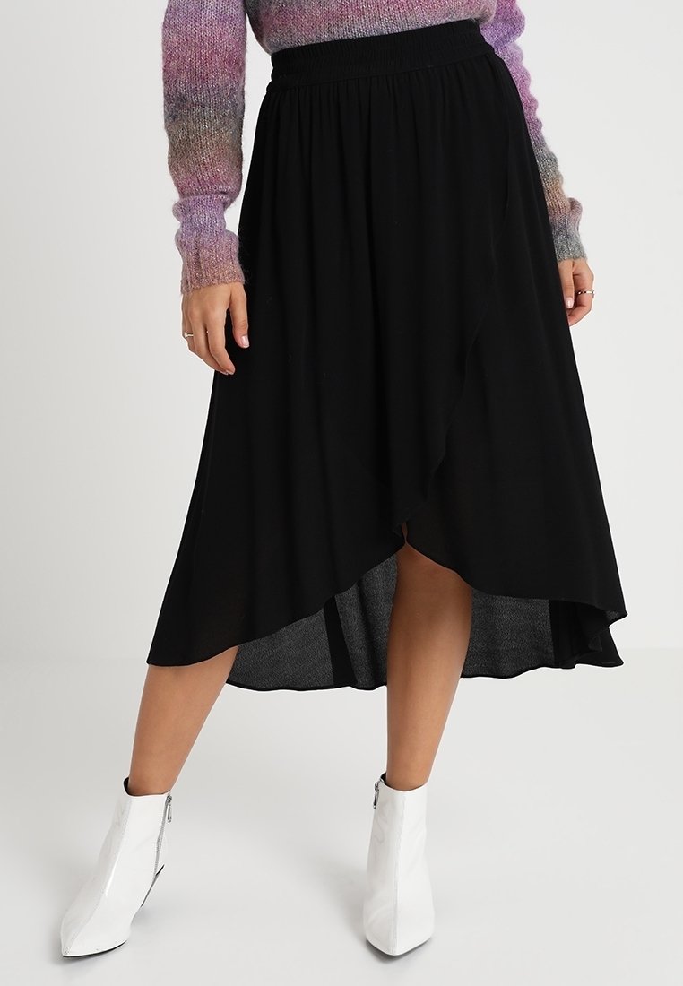 Musta kietaisuhame, jossa on korkea-matala helma, valmistettu kevyestä kankaasta. Yhdistetty valkoisiin nilkkureihin ja moniväriseen neulepuseroon.