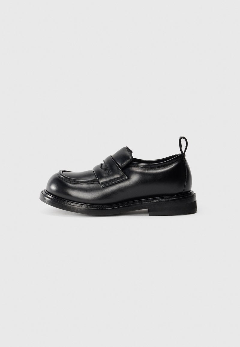 Black leather loafer with a strap across the top, rounded toe, low heel, and a pull tab on the back against a plain background.
