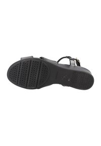 Sandal nero con suola in gomma piatta e testurizzata, cinturino regolabile e piccoli dettagli dorati. Presenta un motivo orizzontale sul cinturino.