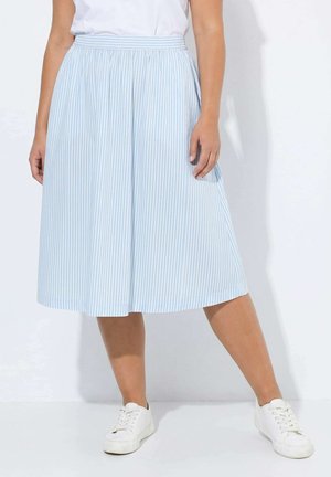 Mujer con falda midi de rayas verticales en azul claro y blanco con cintura elástica y zapatillas blancas, de pie frente a un fondo blanco.