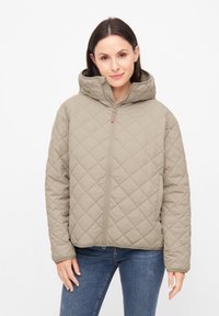 Gequilted, beige jas met capuchon, met een gevoerd textuur, ritssluiting aan de voorkant en twee zijzakken. Het ontwerp heeft een relaxed fit en een eenvoudige stijl.