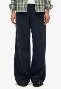 Marineblauwe wijde sweatpants van zachte stof met een elastische band, met zijzakken en een subtiele logodetail.