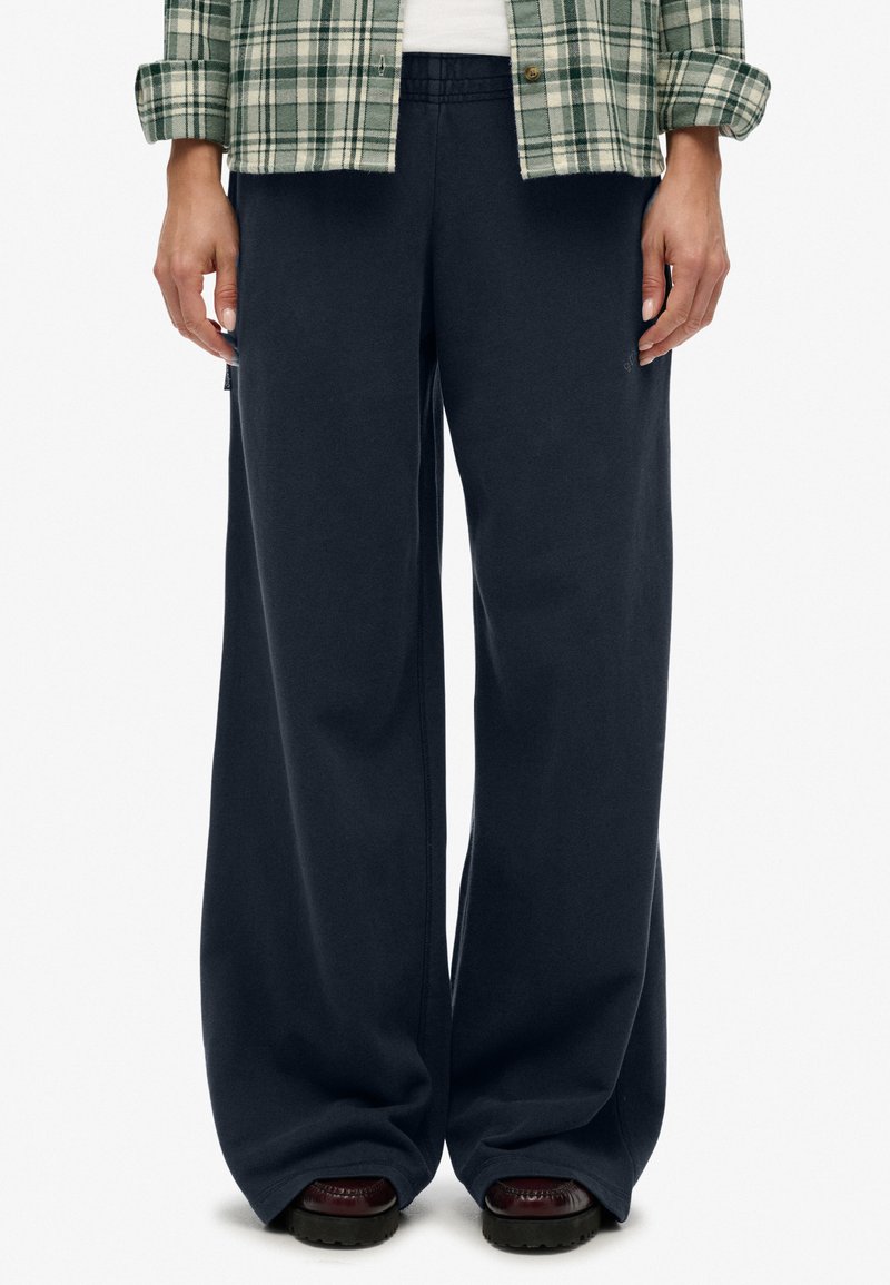 Marineblauwe wijde sweatpants van zachte stof met een elastische band, met zijzakken en een subtiele logodetail.