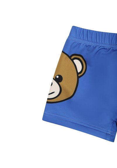 Pantaloni da bagno blu realizzati in tessuto morbido, con una grande grafica di un orso bruno sul lato sinistro. Vita elastica per il massimo comfort.