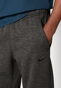 Nike szürke sportnadrág textúrált anyagból. Rugalmas derékkal és oldalzsebbel rendelkezik, diszkrét logóval.