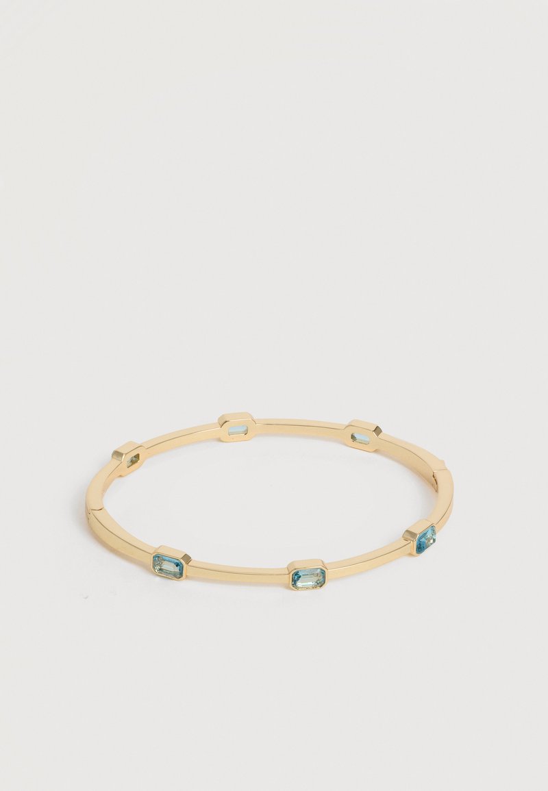 Χρυσό βραχιόλι με έξι ορθογώνιες μπλε πολύτιμες πέτρες ισορροπημένα τοποθετημένες γύρω από το βραχιόλι σε ουδέτερο φόντο.