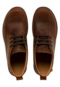 Zapatos de cuero marrón con un acabado suave, puntera redonda, cordones marrones y interior en tono beige. Presentan un pequeño logo grabado y un lazo en el talón.