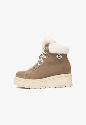 Bottines en suède beige avec un col en fausse fourrure, des lacets robustes, des détails en métal doré et une épaisse semelle plateforme blanche.